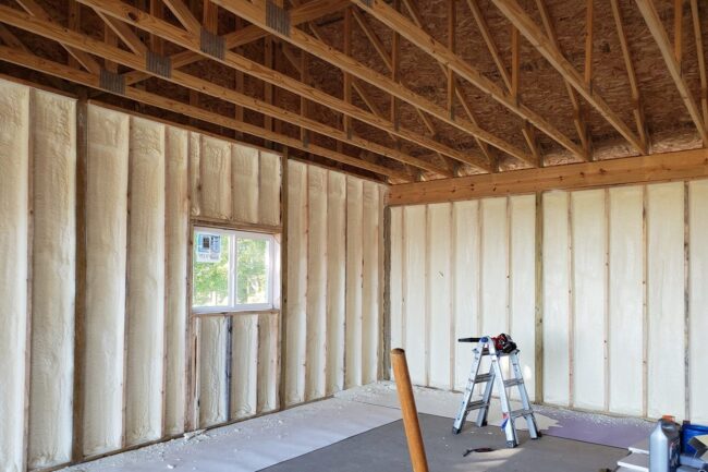 modernizacja budynku Wnętrze budynku z widoczną izolacją ścian wewnętrznych wykonaną pianką poliuretanową oraz konstrukcją drewnianą stropu.