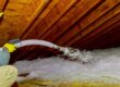Proces docieplania poddasza za pomocą materiału sypkiego, zapewniającego skuteczną izolację termiczną pomiędzy belkami drewnianymi konstrukcji.
